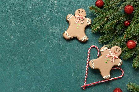 Christmas sweet gingerbread cookies, candy canes and fir branches with balls on green background