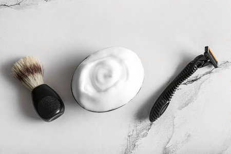 Bowl of shaving foam with razor and brush on grunge white backgroundの写真素材