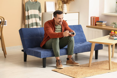 Handsome man playing video game on sofa in living room