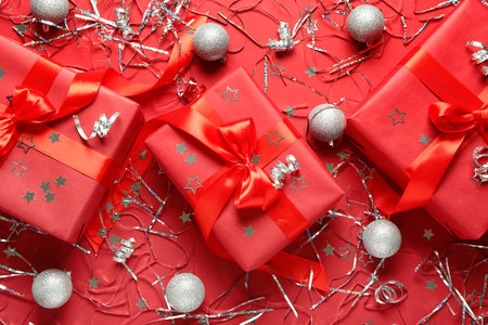 Christmas gift boxes with balls and confetti on red backgroundの写真素材