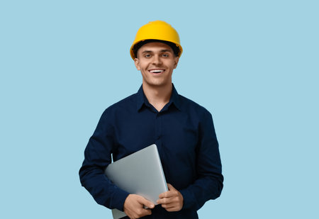 Young male engineer with laptop on blue backgroundの写真素材