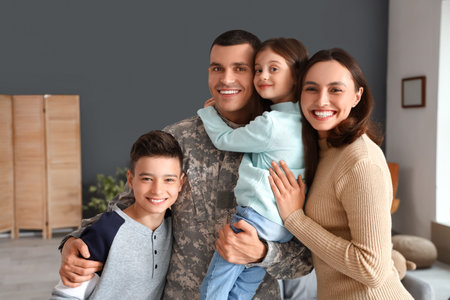 Soldier with his wife and little children hugging at homeの写真素材