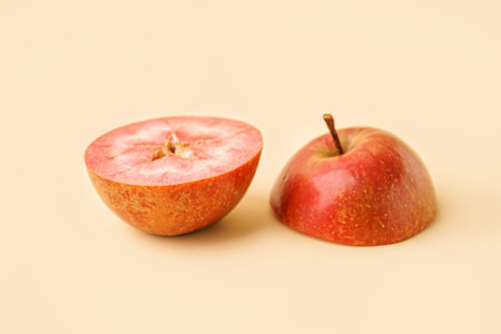 Halves of sweet pink apple on yellow background
