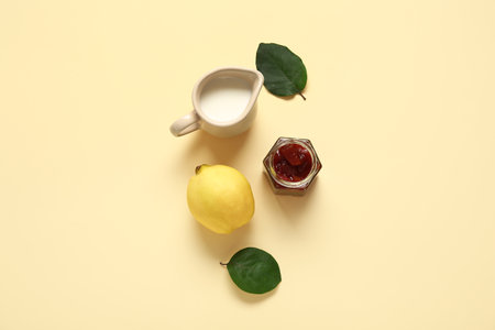 Quince fruit with milk jug and jar of jam on beige backgroundの写真素材