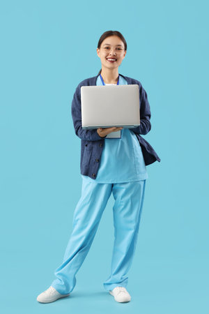 Asian medical intern with laptop on blue backgroundの写真素材