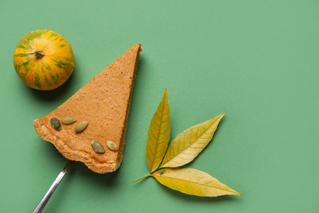 Piece of tasty pumpkin pie and autumn leaf on green backgroundの写真素材
