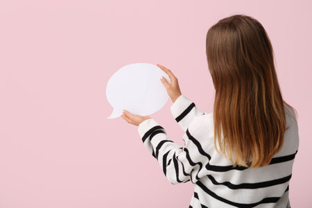 Pretty young woman holding blank speech bubble on pink background, back viewの写真素材