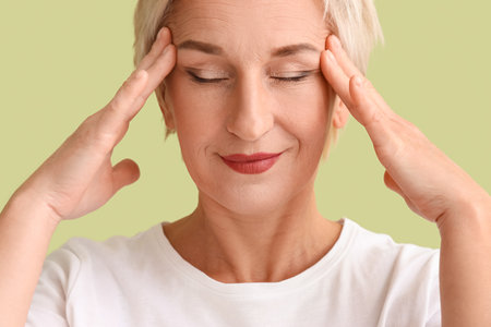 Mature woman doing face building exercise on green background, closeupの写真素材