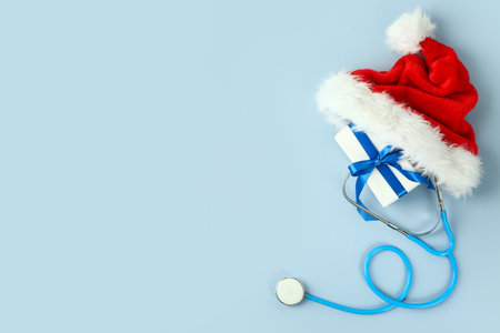 Santa hat with stethoscope and Christmas gift on color backgroundの写真素材