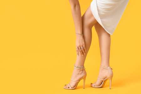 Woman in heels with silver jewelry on yellow backgroundの写真素材