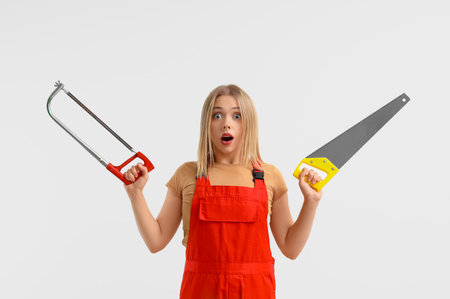 Surprised female worker with tools on light backgroundの写真素材