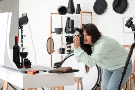 Female food photographer taking picture of wine with grapes in studio