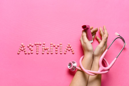Child's hands with inhaler, stethoscope and word ASTHMA made of pills on pink backgroundの写真素材
