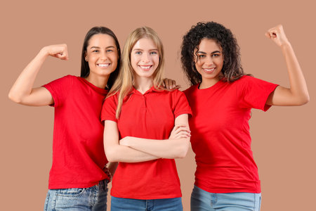 Beautiful young women showing muscles on beige background. Women history monthの写真素材