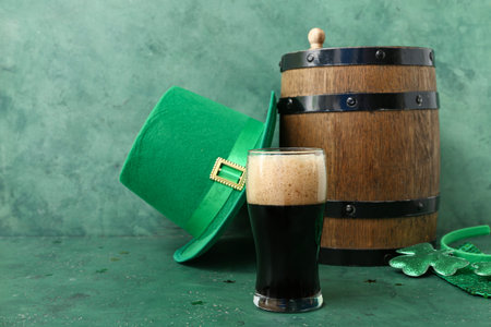 Barrel and glass of dark beer with leprechaun hat for St. Patrick's Day celebration on green grunge...