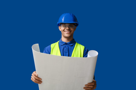 Young male engineer with blueprint on blue backgroundの写真素材