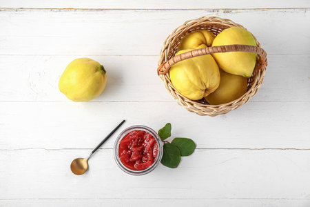 Jar of sweet jam with quince fruits on white wooden backgroundの写真素材