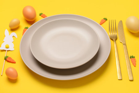 Beautiful Easter table setting served with eggs, toys and bunnies on yellow backgroundの写真素材