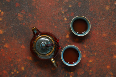 Ceramic cups of hot matcha tea with traditional teapot on brown backgroundの写真素材