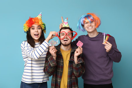 Young friends in funny disguise with whistles and paper stickers on blue background. April fool's day celebrationの写真素材