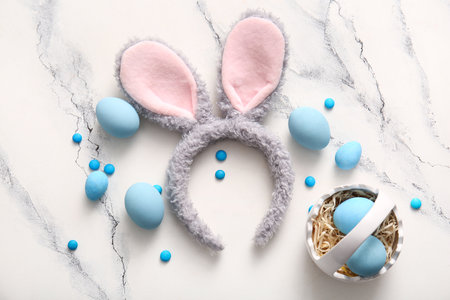 Bunny ears with Easter eggs and candies on white marble backgroundの写真素材