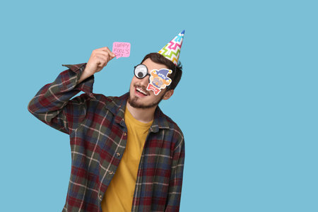 Handsome young man in funny disguise with stickers on blue background. April fool's day celebrationの写真素材