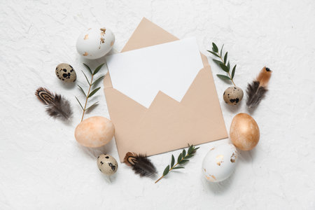 Envelope with blank card, Easter eggs, feathers and leaves on white backgroundの写真素材