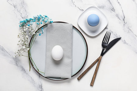 Beautiful table setting for Easter with eggs and flowers on white grunge background