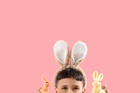 Cute little boy wearing bunny ears with Easter rabbits on pink background, closeupの写真素材