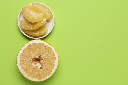Half of sweet pomelo fruit and plate with slices on green backgroundの写真素材