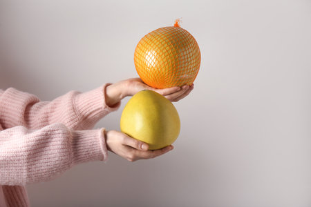 Female hands holding sweet pomelos on white backgroundの写真素材