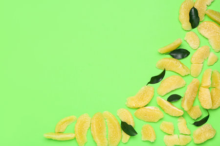 Pomelo fruit pieces and leaves on green background