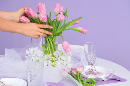 Female hands with bouquet of tulip flowers on table served for International Women's Day celebrationの写真素材