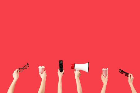 Hands holding popcorn, 3D glasses and TV remote and on red backgroundの写真素材