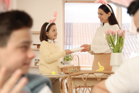 Little girl with her mother setting dining table at home on Easter Day