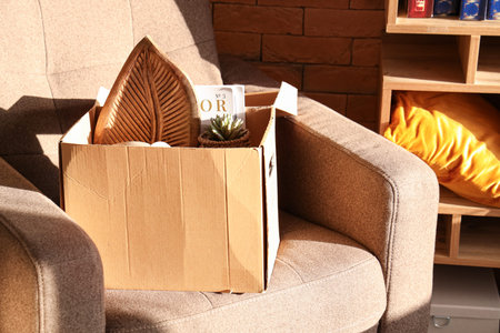 Box of unwanted stuff for garage sale on armchair in room