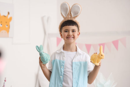 Cute little boy wearing bunny ears with Easter rabbits at home