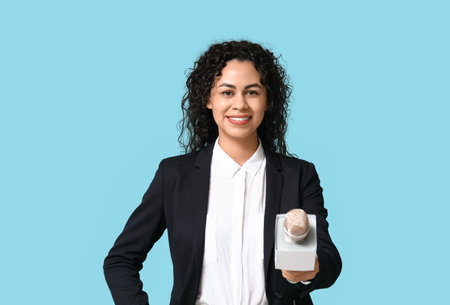 Beautiful young happy African-American female journalist with microphone on blue backgroundの写真素材