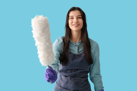Young woman in apron with pp-duster on blue backgroundの写真素材