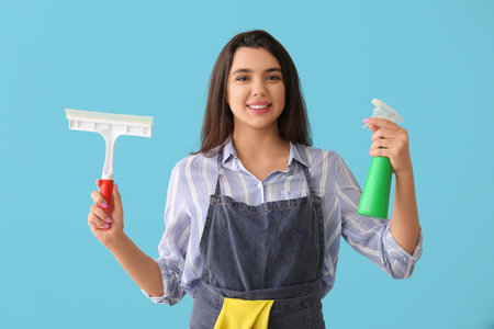 Young woman with squeegee and detergent on blue backgroundの写真素材
