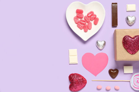 Different tasty sweets with paper hearts and gift box on purple background. Valentine's Day celebrationの写真素材