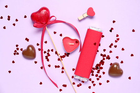 Tasty sweets with candle and heart-shaped confetti on purple background. Valentine's Day celebration