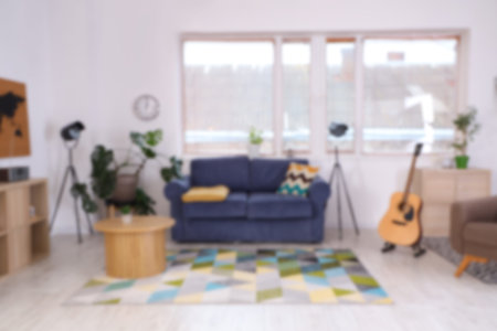 Blurred view of stylish living room with sofa, table and guitarの写真素材