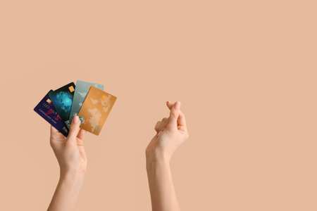 Woman with credit cards making heart gesture on beige backgroundの写真素材