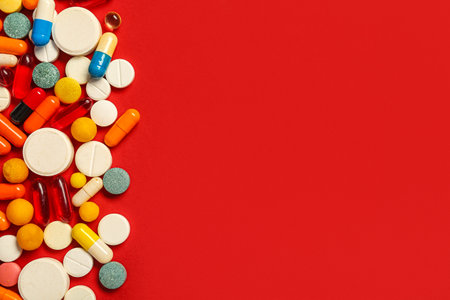 Heap of different pills on red backgroundの写真素材