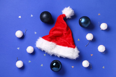 Santa Claus hat with Christmas balls and confetti on blue backgroundの写真素材