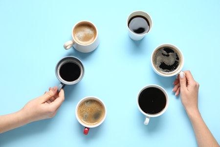 Frame made of female hands with cups of hot coffee on blue backgroundの写真素材
