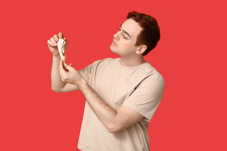 Handsome young man with vibrator on red background