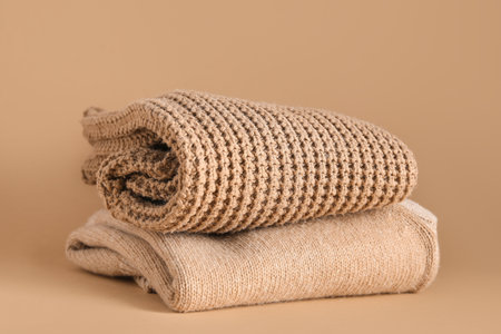 Stack of beautiful stylish sweaters on beige backgroundの写真素材