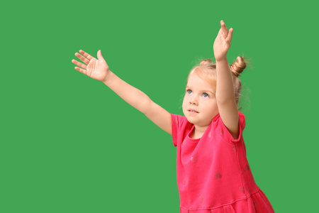Cute little girl opening arms for hug on green backgroundの写真素材